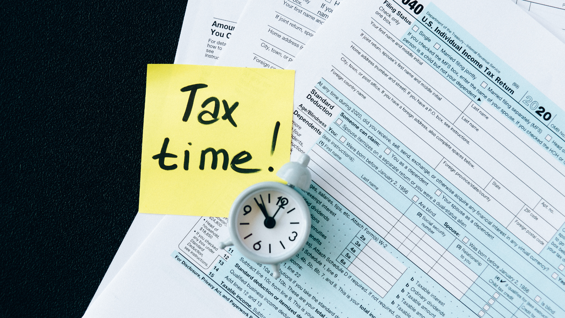 Une montre, des factures et l'inscription 'Tax Time' sur un papier, représentant la période cruciale de déclaration des impôts. comment préparer votre déclaration d'impôt sans stress.